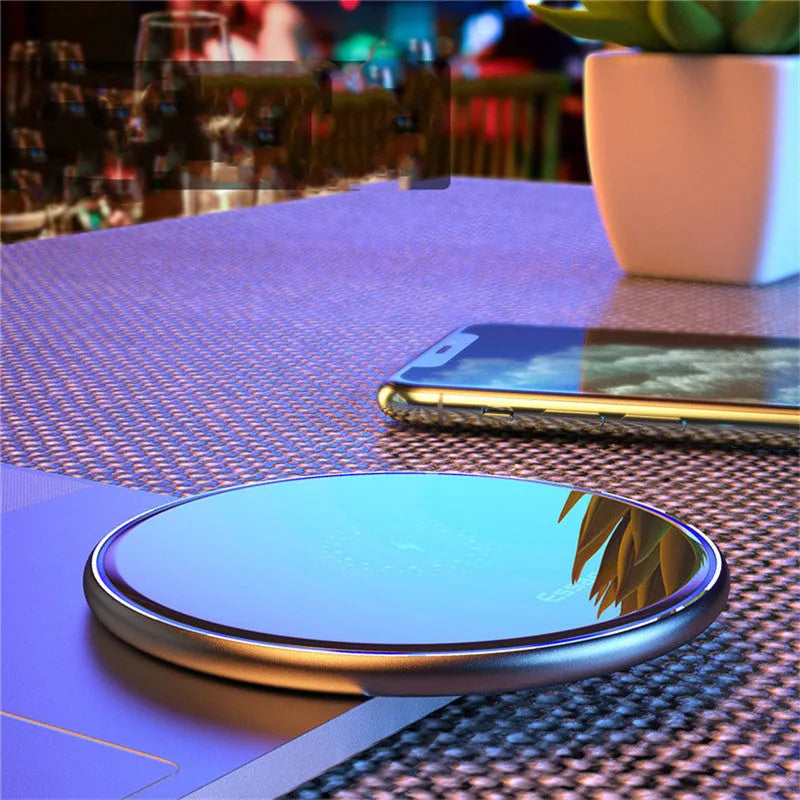 Black wireless charging pad on table with phone charging and blue LED indicator light