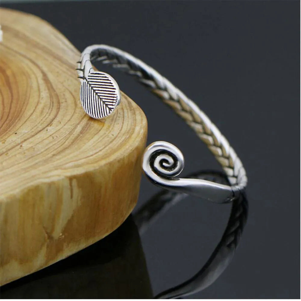 Close-up of a silver-toned women's bracelet with a detailed Chinese-style fish charm and an adjustable opening clasp.