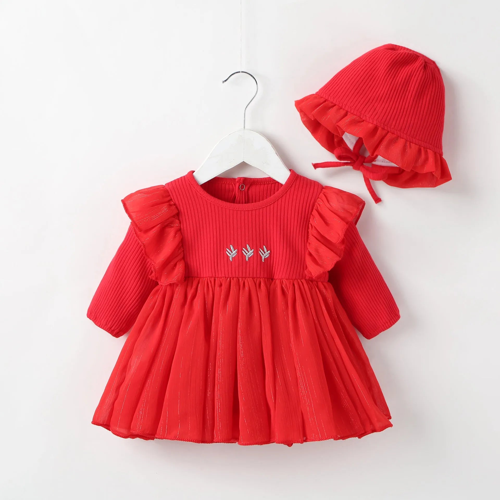 Baby girl wearing a fluffy cotton princess dress in pink, available in red and white, sizes 59cm to 80cm.