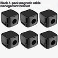 White and black magnetic cable clips holding a USB cable against a wooden desk edge.
