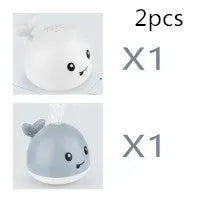Whale-shaped electric bath toy spraying water with flashing lights, floating in baby bathtub