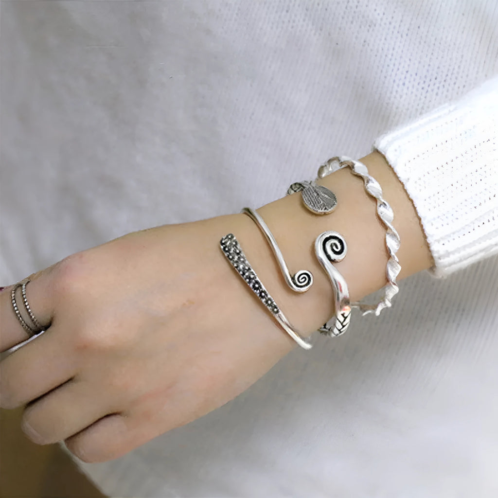 Close-up of a silver-toned women's bracelet with a detailed Chinese-style fish charm and an adjustable opening clasp.