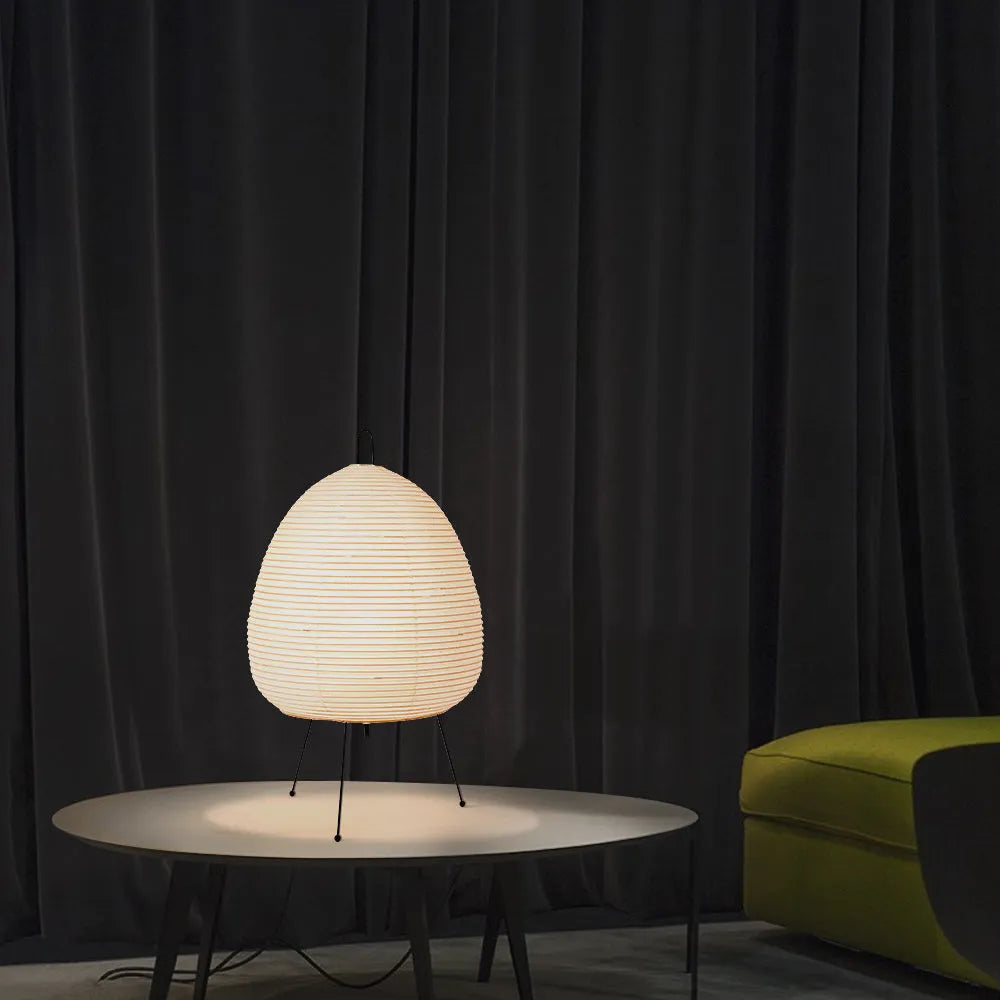 Japanese style rice paper table lamp with aluminium base on a wooden table.