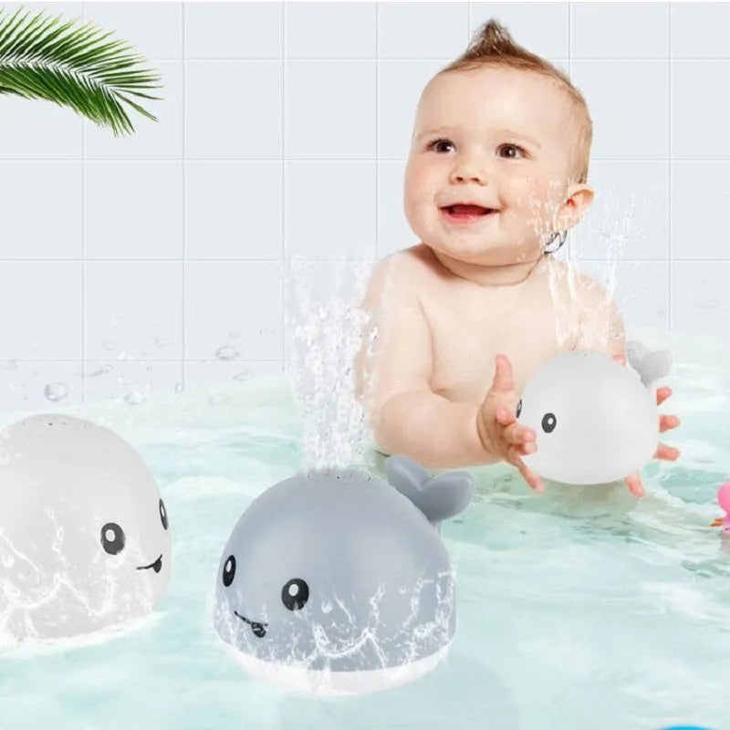 Whale-shaped electric bath toy spraying water with flashing lights, floating in baby bathtub