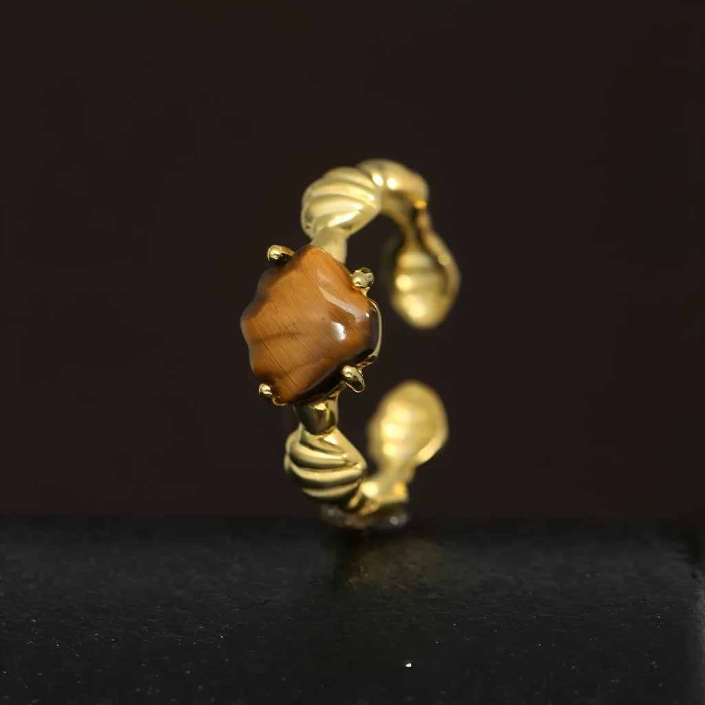 Women's silver ring with shell design and Tiger Eye stone on an adjustable band.