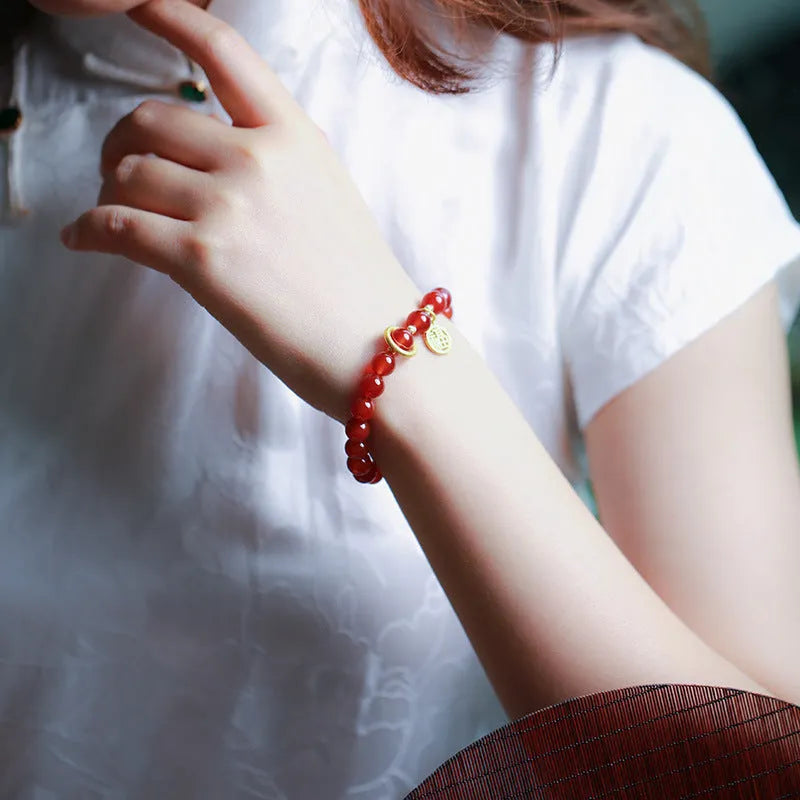 Natural red agate bead bracelet with woven design and blessing card on a neutral background.