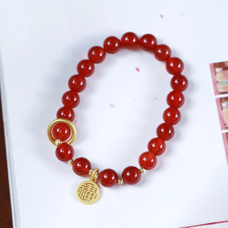 Natural red agate bead bracelet with woven design and blessing card on a neutral background.
