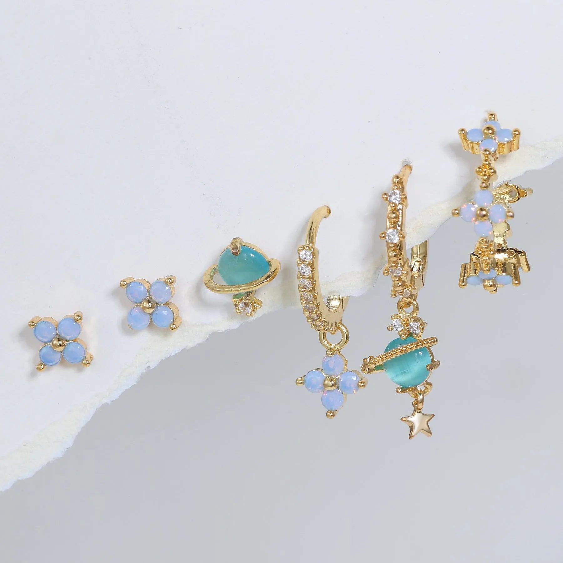 Gold and silver flower-shaped ear studs with blue zircon mosaic decoration.