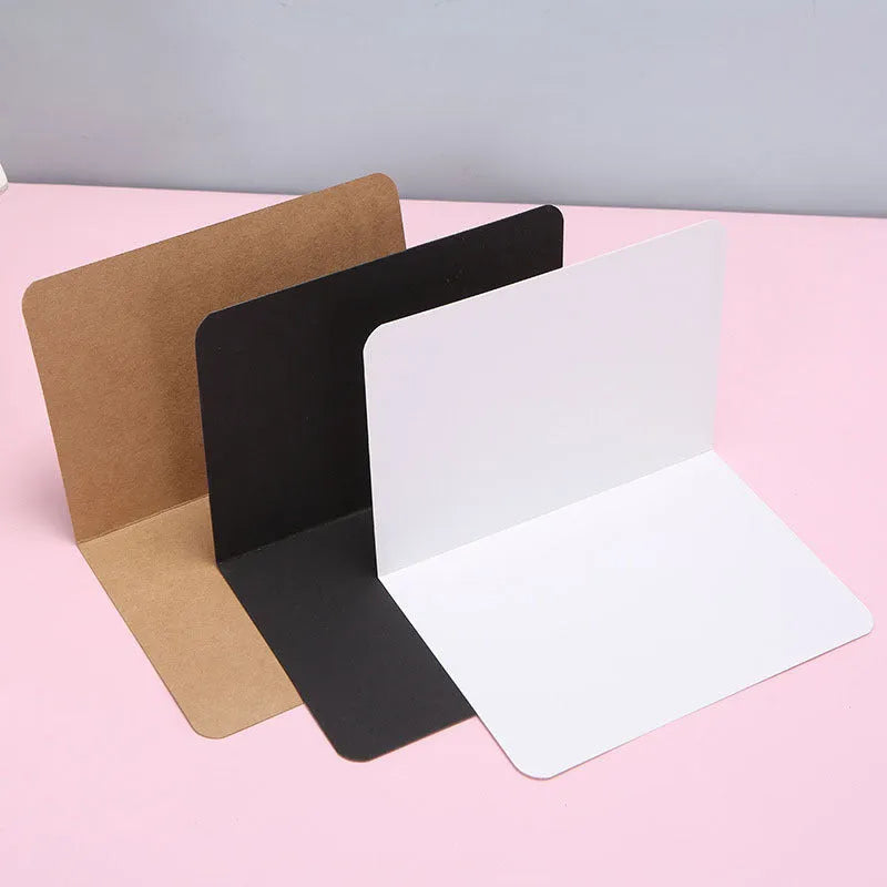 Pack of 100 blank folded kraft paper greeting cards in 10x15cm size, showing black, cowhide brown, and white colour options