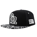 A black cotton baseball cap with embroidered lettering on the front, showing the adjustable strap at the back.