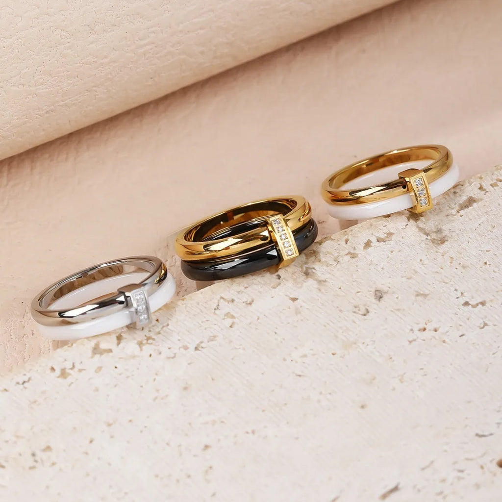 Women's heart-shaped titanium steel ring with glossy stitching and zirconium detail in gold black, golden white, and steel white.