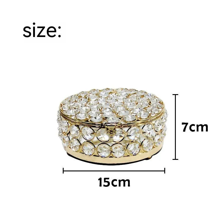 French gold iron jewelry storage box with a clear crystal glass lid on a wooden surface.