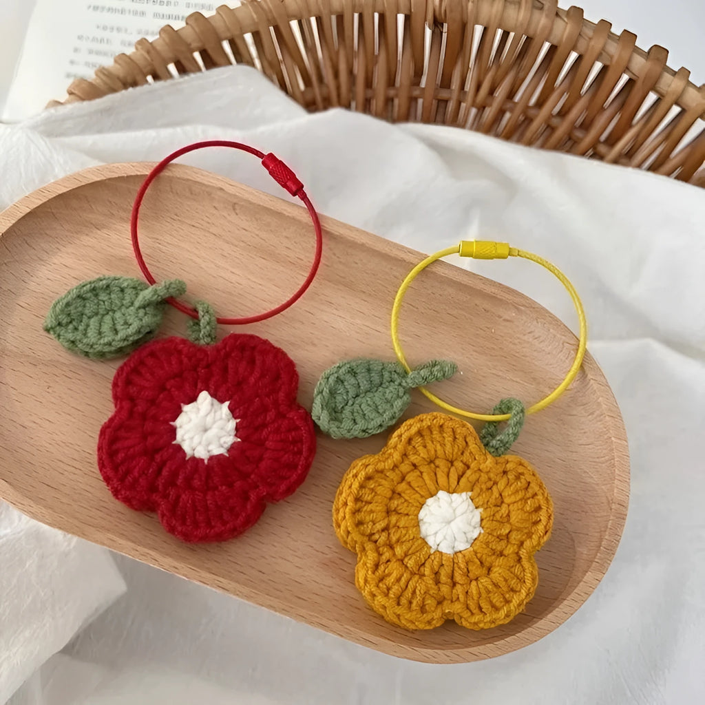 Close-up of a small red hand-crocheted wool flower pendant on a white background.