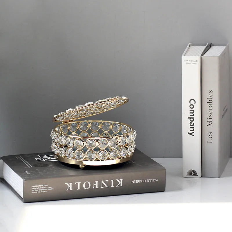 French gold iron jewelry storage box with a clear crystal glass lid on a wooden surface.