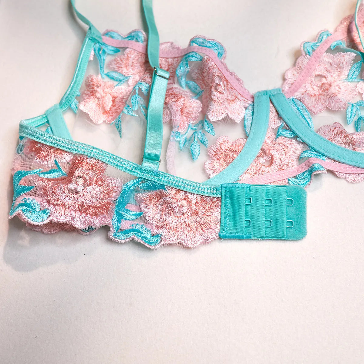 Pink embroidered women's bikini set with a matching mesh pettiskirt laid flat.