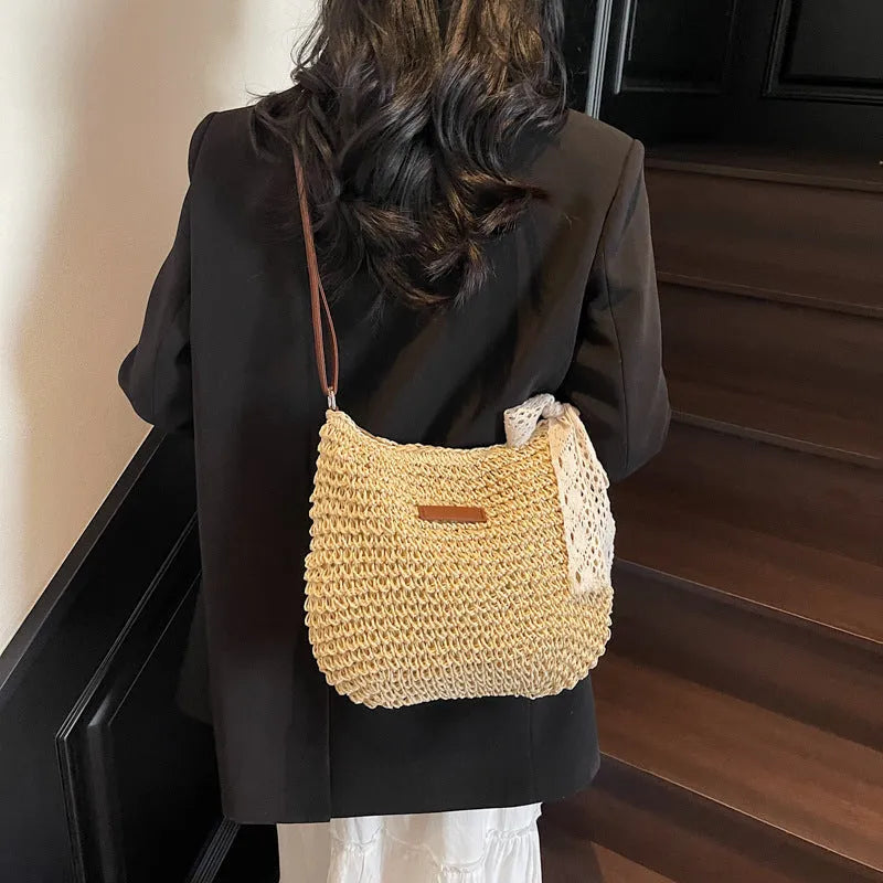 Women's khaki woven straw messenger bag with hollowed pattern and single shoulder strap.