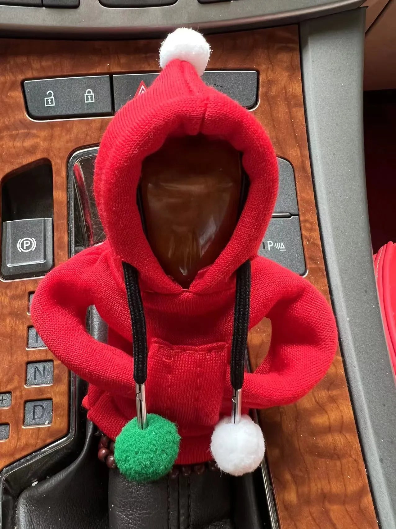 Knitted gear lever hooded sweater with coloured pom poms on car gearstick
