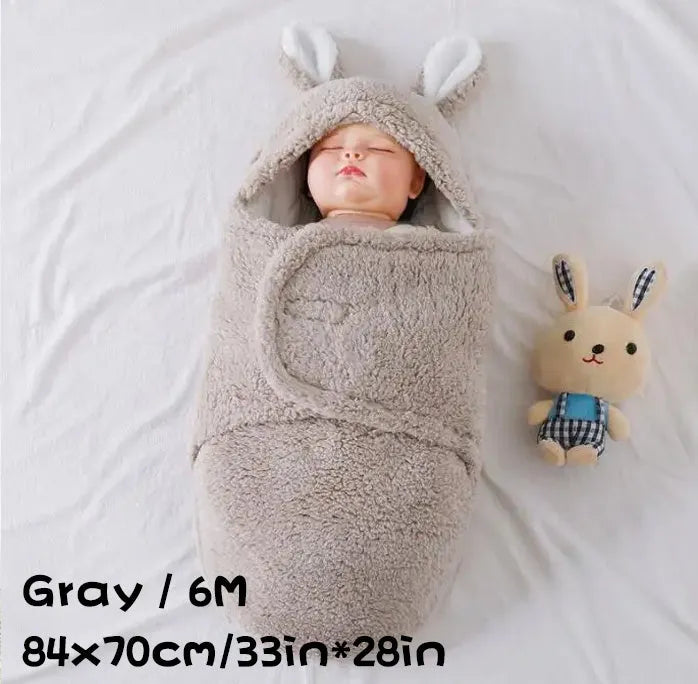 A baby wearing a soft grey fleece sleeping bag with hook-and-loop shoulder straps.