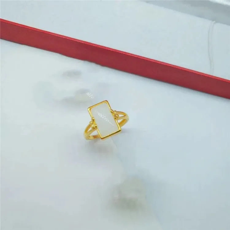 A gold-coloured adjustable ring with a large central green artificial gemstone, showing the national style design.