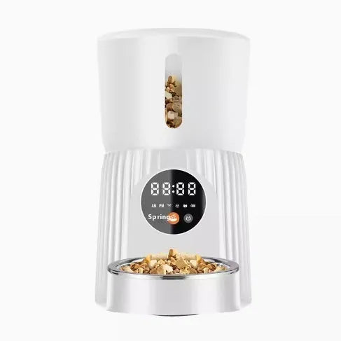 Black automatic pet feeder with digital display and detachable bowl on a kitchen floor.