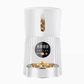 Black automatic pet feeder with digital display and detachable bowl on a kitchen floor.