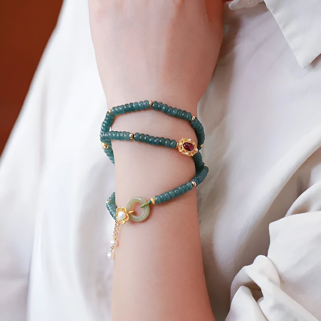Close-up of a blue water jade and abacus bead bracelet with tourmaline rings and freshwater pearls.