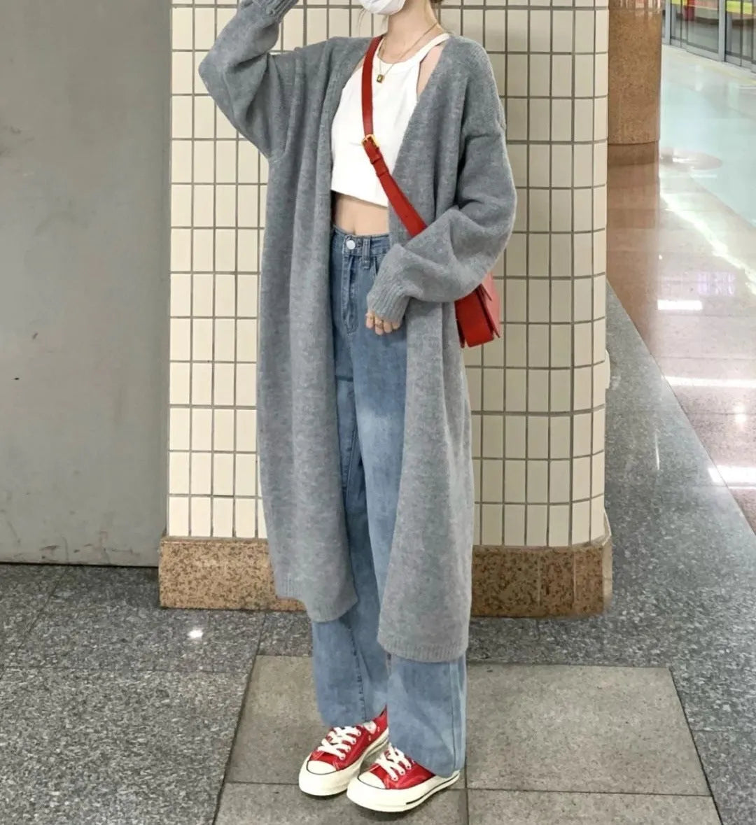 Dark grey loose knitted women's cardigan with a 3D pattern, shown open over a white top.
