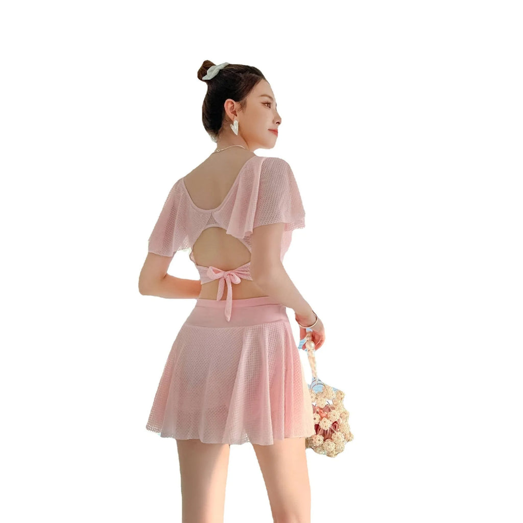 Women's solid colour two-piece swimsuit set with a skirt, shown in white, black, or pink.