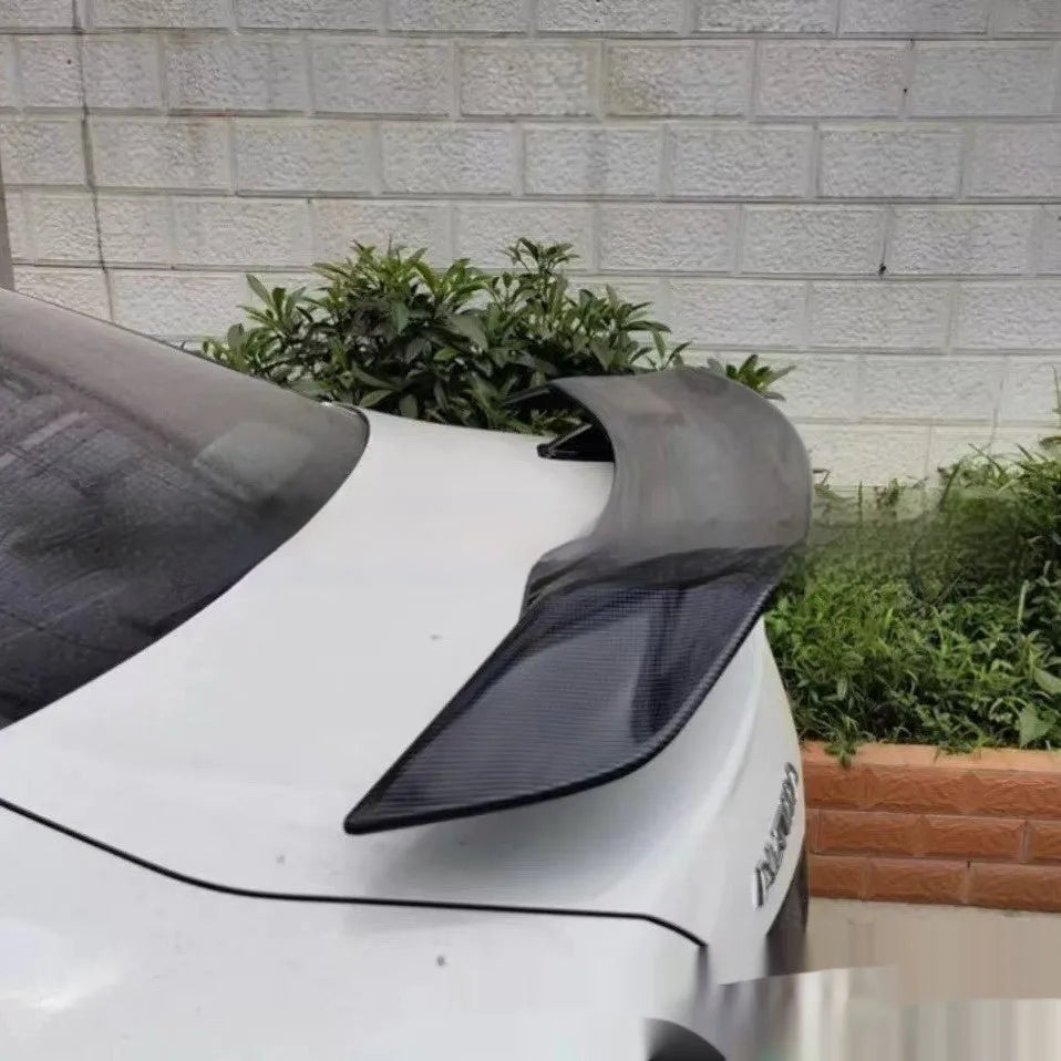 A universal punch-free ABS plastic car tail wing spoiler showing bright black, white, and carbon pattern finish options.