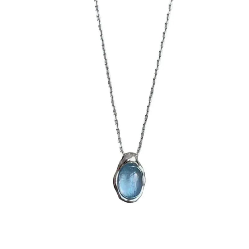 Close-up of a navy blue geometric water drop pendant on a platinum-colour adjustable cross chain necklace.