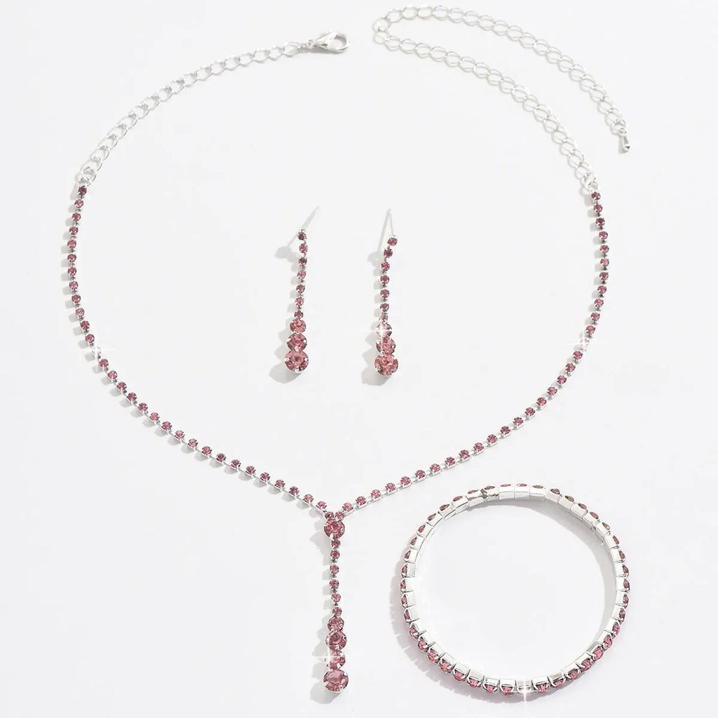 Three-piece bridal jewellery set showing necklace, bracelet and earrings with rhinestone pendant and heart-shaped design