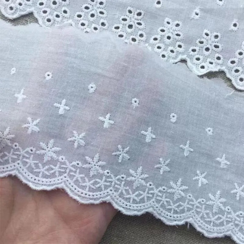 Cotton embroidered lace trim on roll showing cutout pattern, with width measurement examples