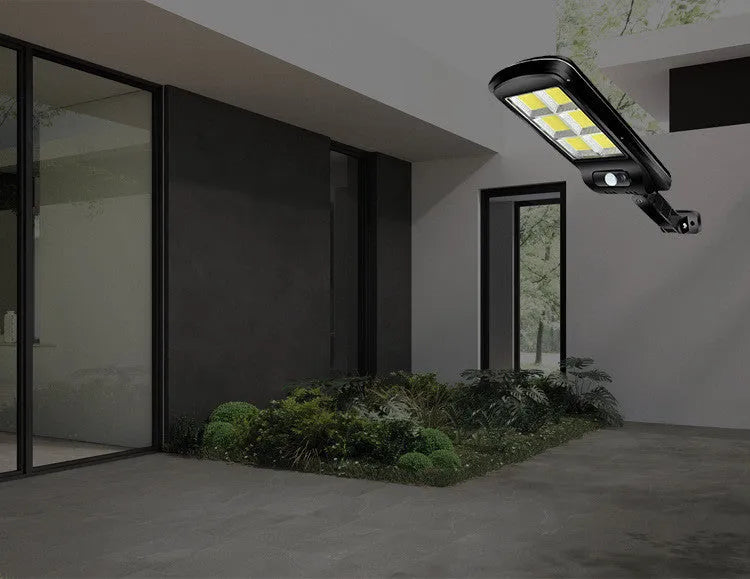 Black solar-powered outdoor security light with motion sensor on a wall