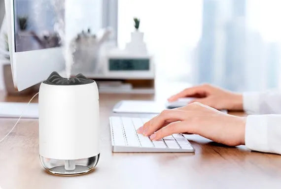 Mini cylindrical USB ultrasonic humidifier in white, pink, or green with warm night light on.
