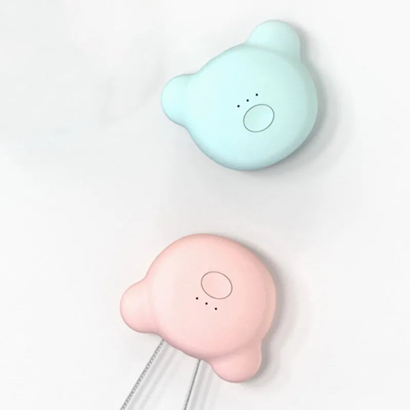 Compact pink USB portable air purifier necklace on a table with charging cable.