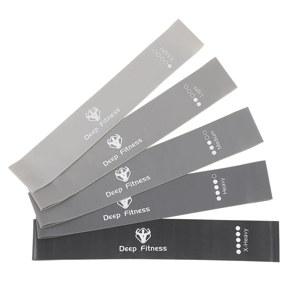 Yoga hip resistance band set in six colours from 0.4mm green to 1.2mm black laid flat on a surface