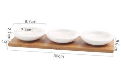 Porcelain ceramic dried fruit dish with three snack compartments on a wooden serving board.
