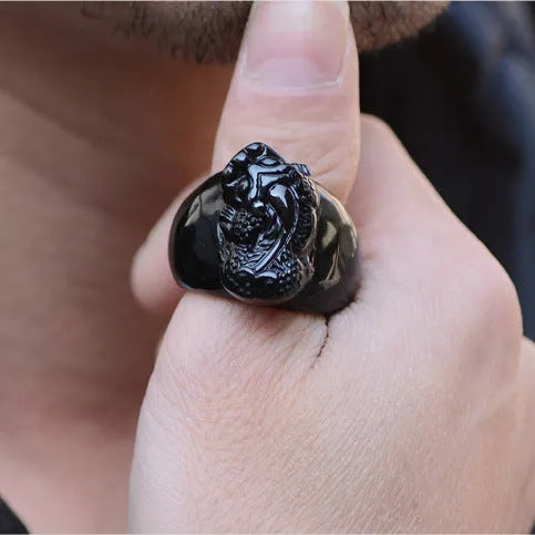 Men's obsidian pixiu thumb ring showing gold sheen and detailed carving on a hand.