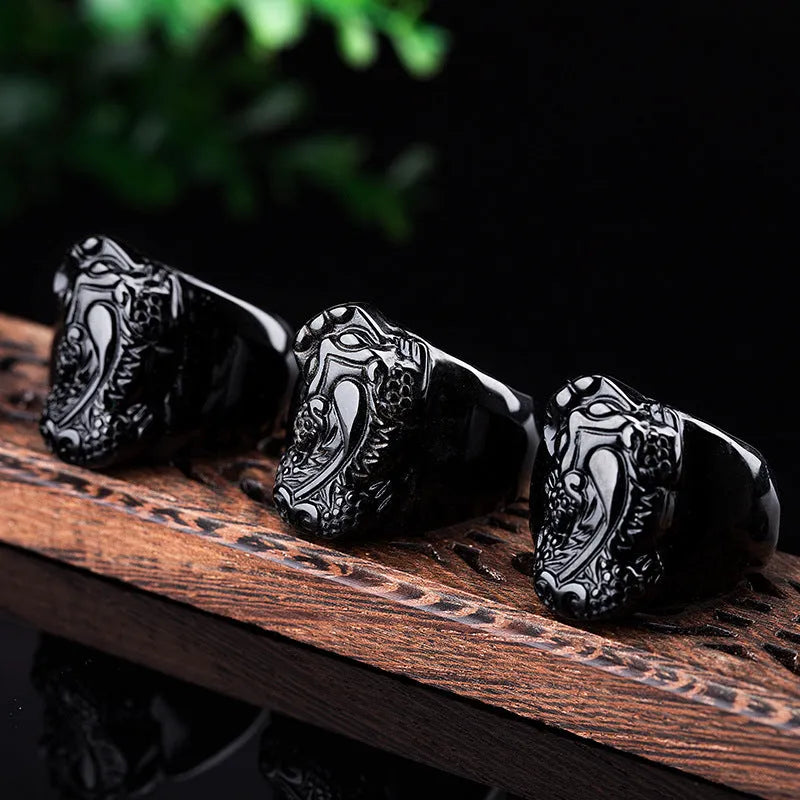 Men's obsidian pixiu thumb ring showing gold sheen and detailed carving on a hand.