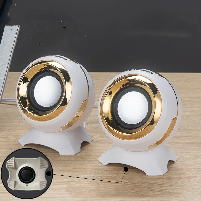 Compact black and gold USB-powered desktop speaker beside a laptop.