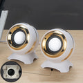 Compact black and gold USB-powered desktop speaker beside a laptop.