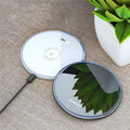 Black wireless charging pad on table with phone charging and blue LED indicator light