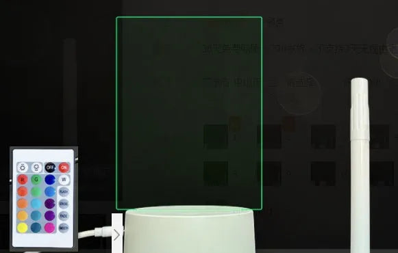 3D acrylic message board night light with remote control and stylus on a desk.