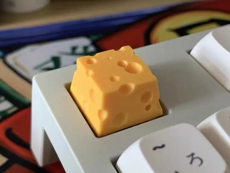 Close-up of a bright yellow resin key cap with a detailed sculpted cheese design.
