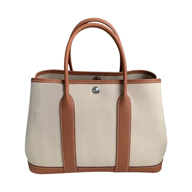 Women's canvas bucket tote bag with leather trim in black colour showing open pocket and crossbody strap