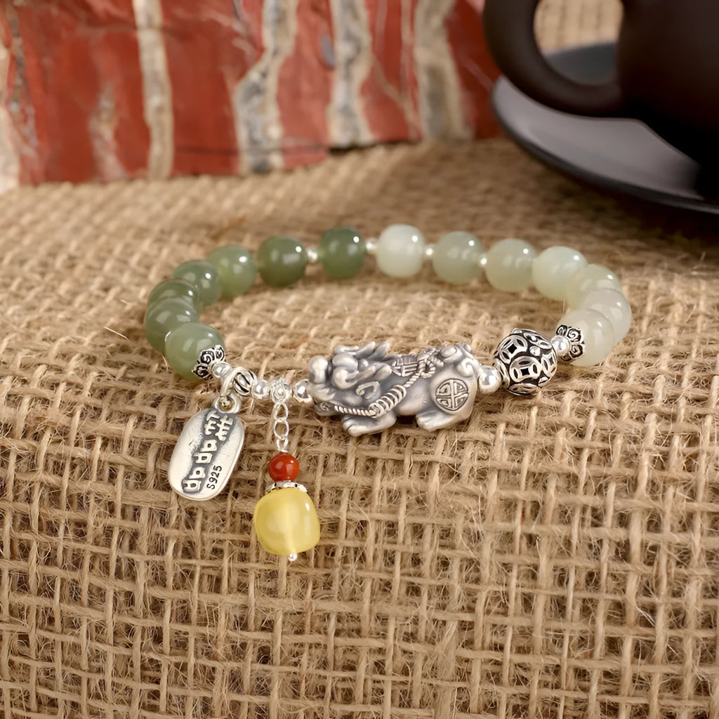 Close-up of a women's silver bracelet with Hetian jade beads and an 8x7mm retro coin charm.