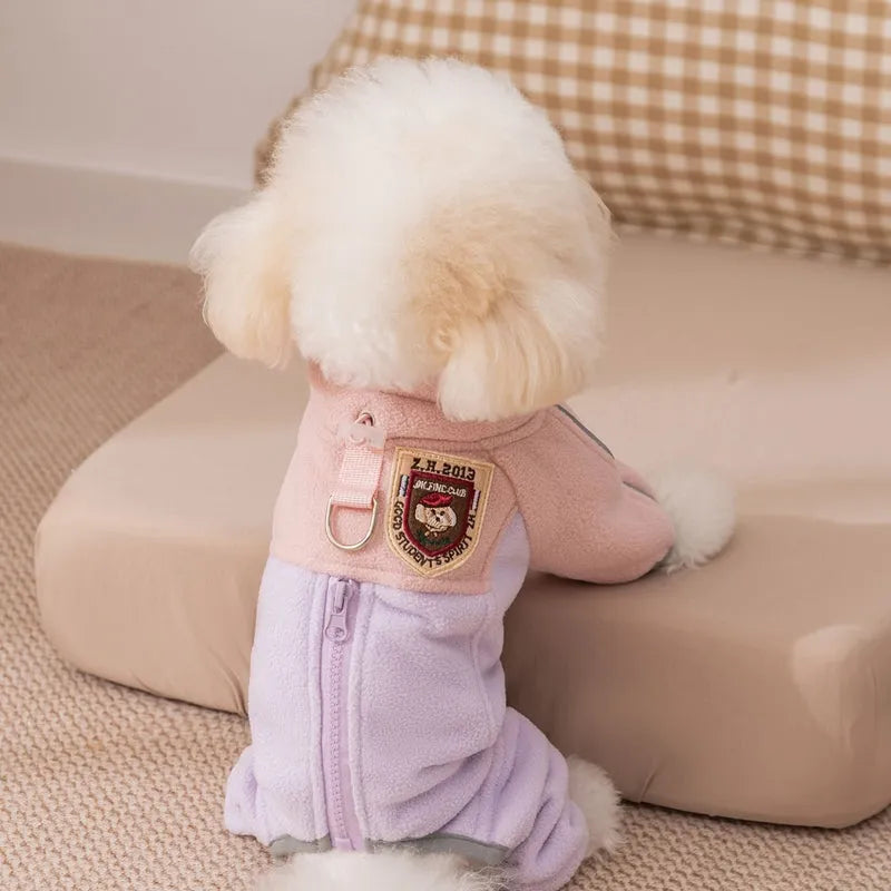 Small dog wearing a colour-block fleece jumpsuit in purple and pink, with full-zip front and leash ring