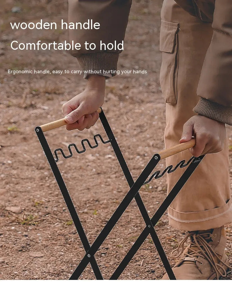 Black iron folding bin rack with wooden handles holding two rubbish bags in an outdoor setting.