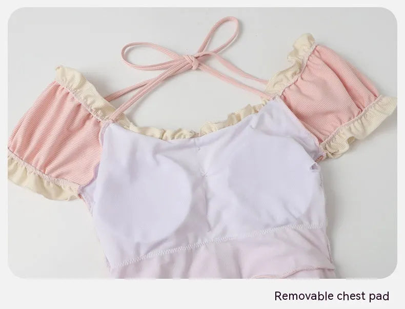 Pink Siamese style conservative one-piece swimsuit for women on a hanger