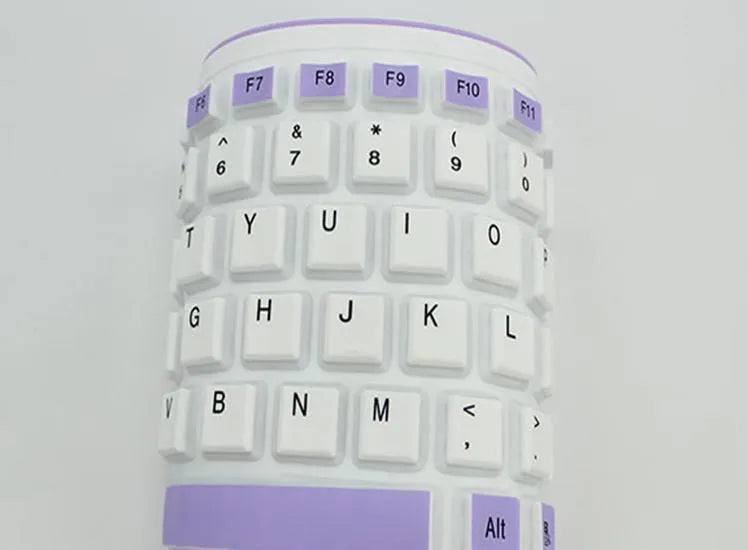 Folding waterproof silicone keyboard in pink with USB cable on a desk